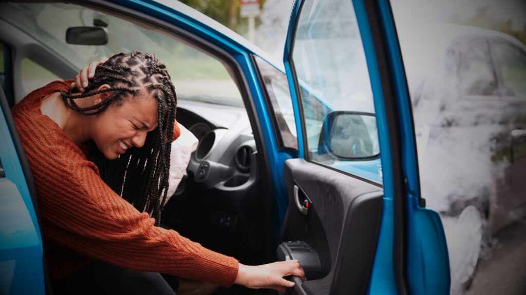 Motor Claims Services, and legal expense's - Young woman distressed after car accident with deployed airbag, holding head, highlighting the need for efficient claims and accident management services.