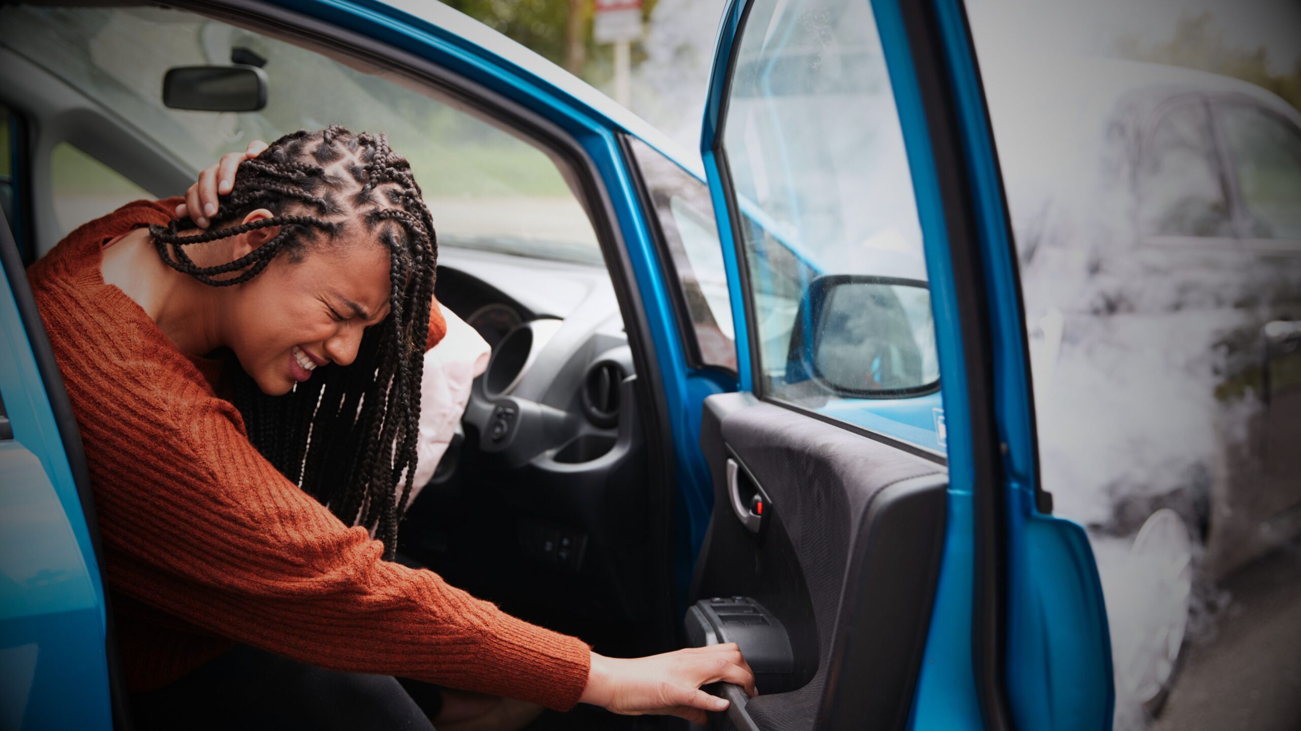 Motor Claims Services, and legal expenses - Young woman distressed after car accident with deployed airbag, holding head, highlighting the need for efficient claims and accident management services.