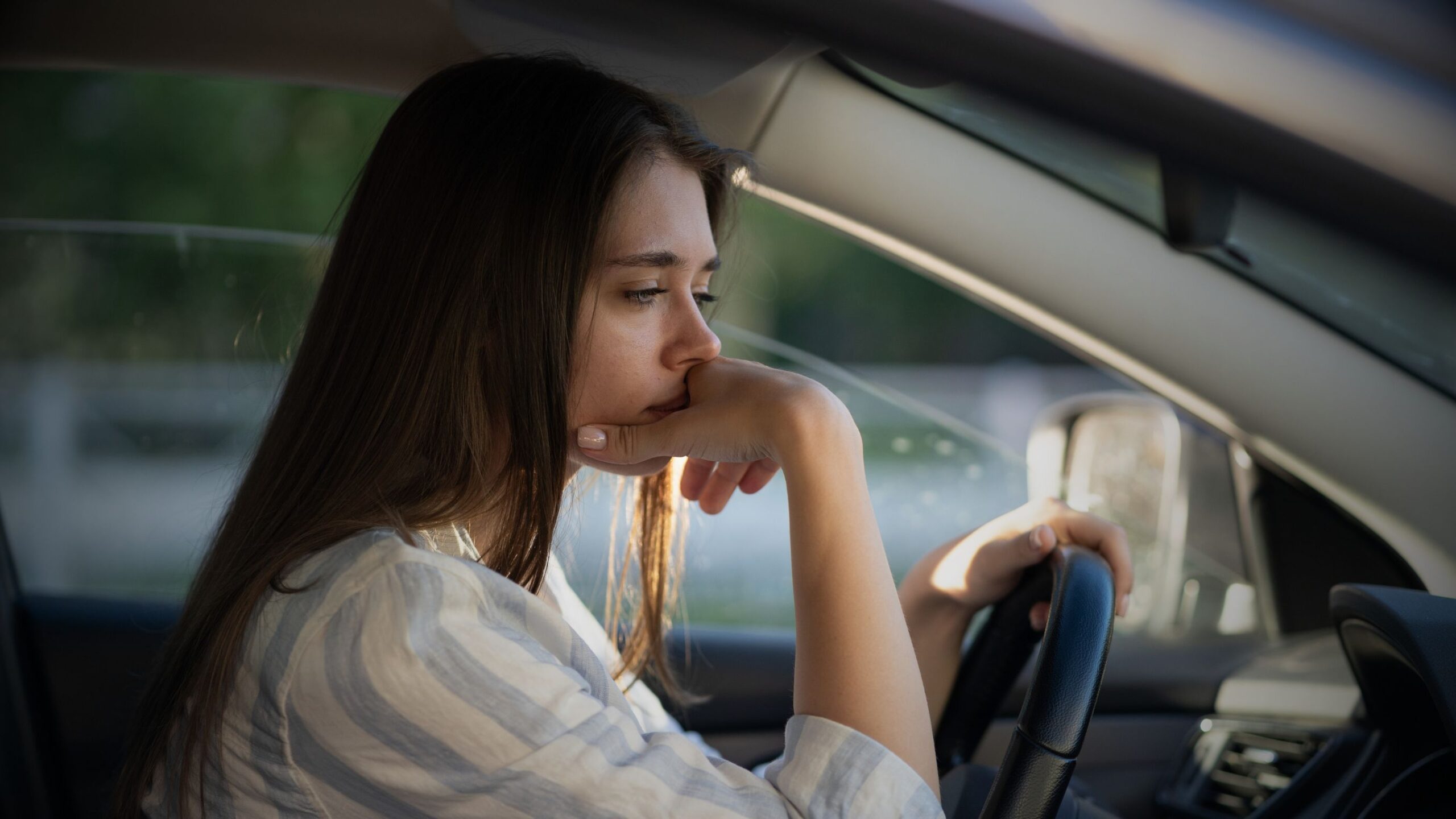 Pensive female driver sitting in her car, looking stressed or worried being a convicted driver.