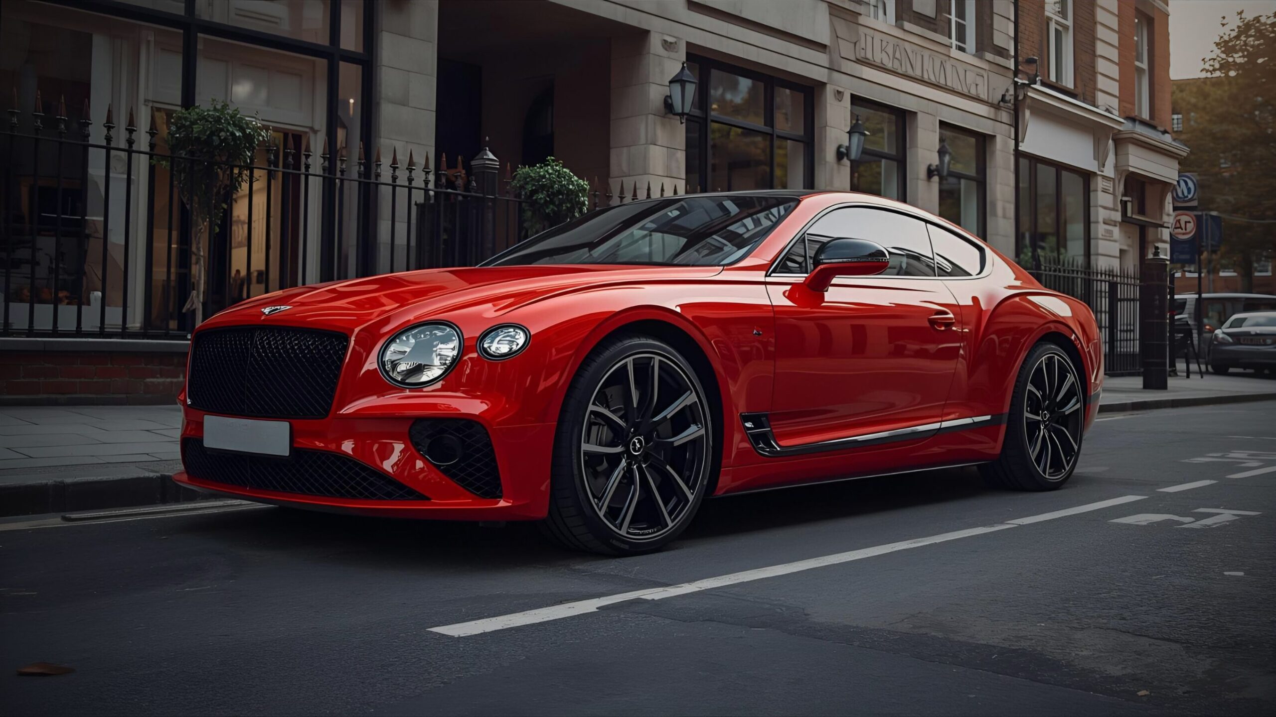Luxury Car: Stunning bright red Bentley Continental GT parked on a city street outside a luxurious, high-end building, symbolising Luxury and High Performance Car Insurance by VINTTRO Cover.