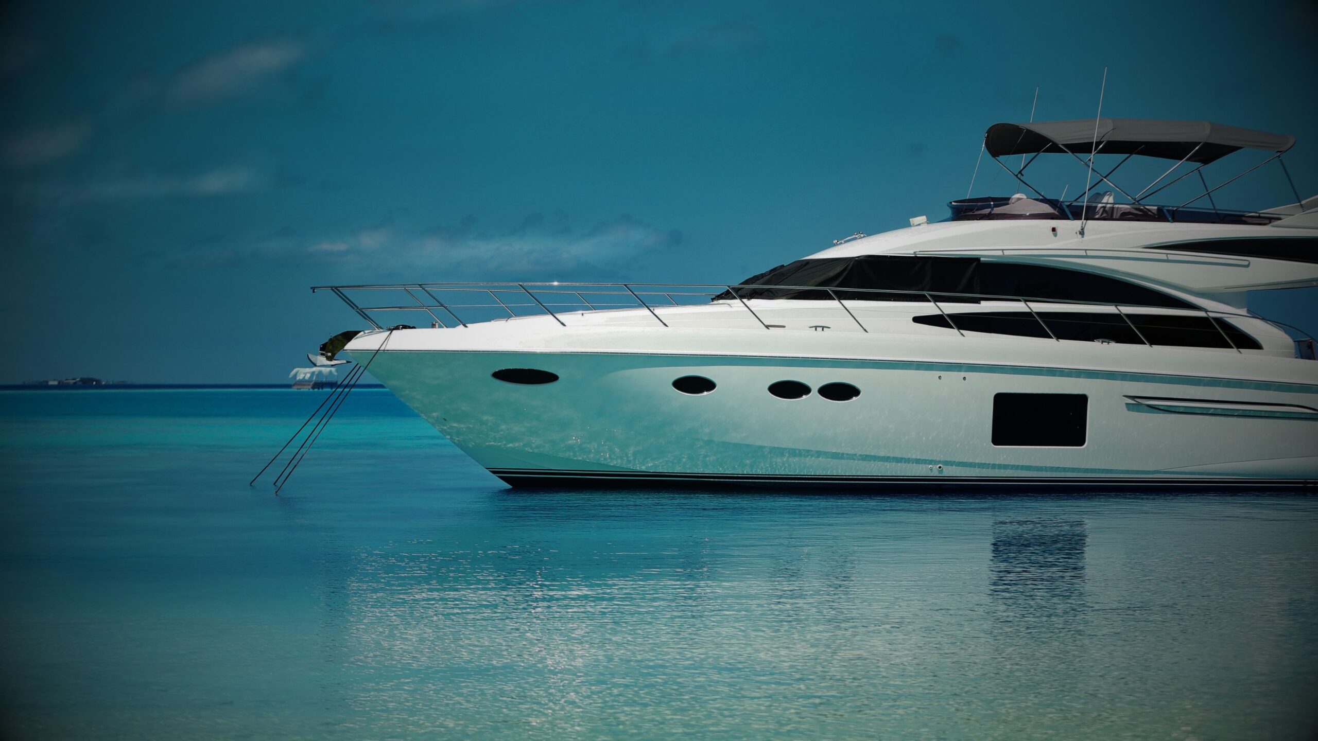 A luxurious white yacht floating on calm, clear turquoise waters under a blue sky, symbolising high-value marine assets and sophisticated lifestyle funding and insurance.