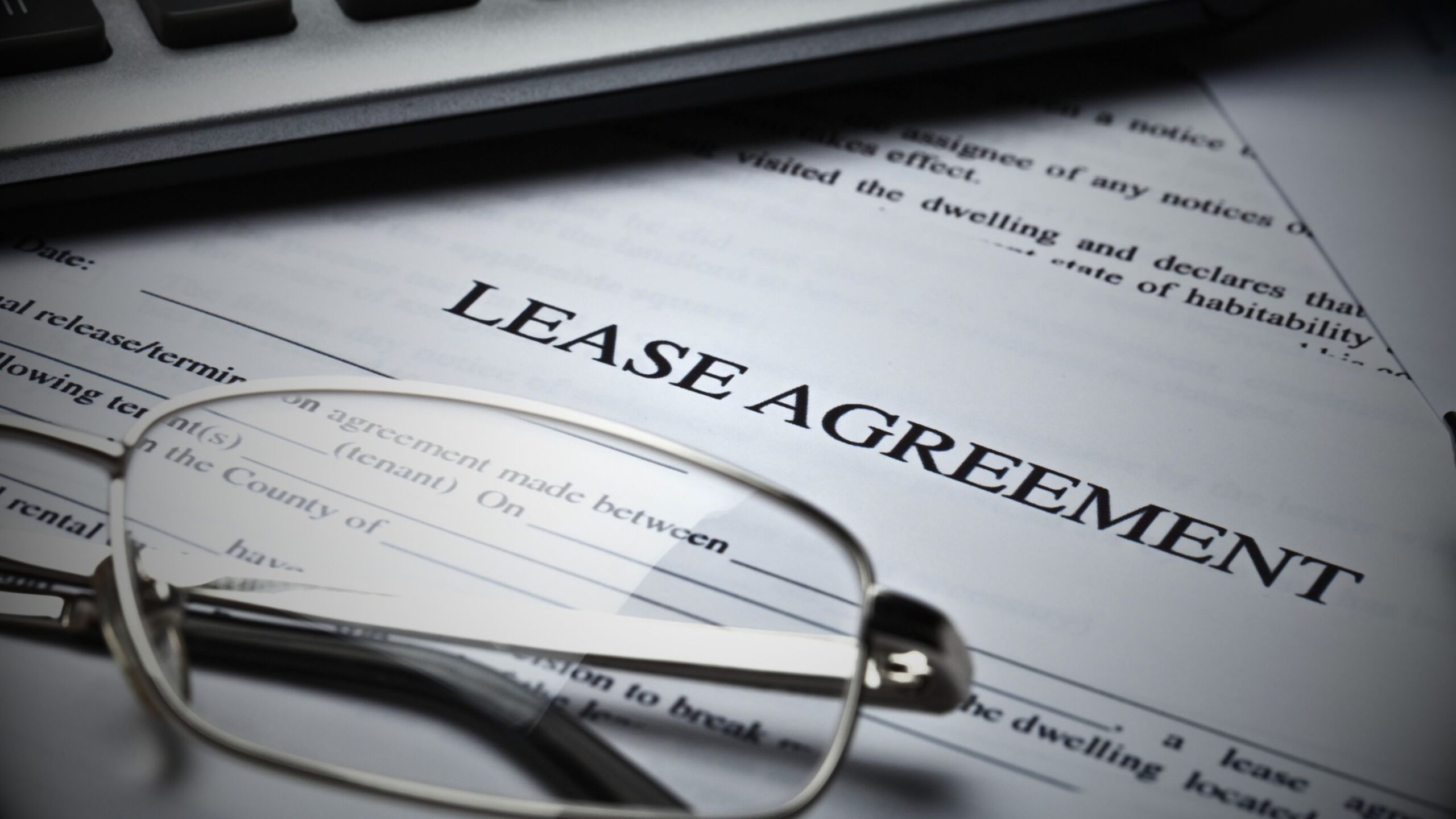 VINTTRO partner legal representation for commercial lease agreement disputes, showing a close-up of a 'Lease Agreement' document under reading glasses.