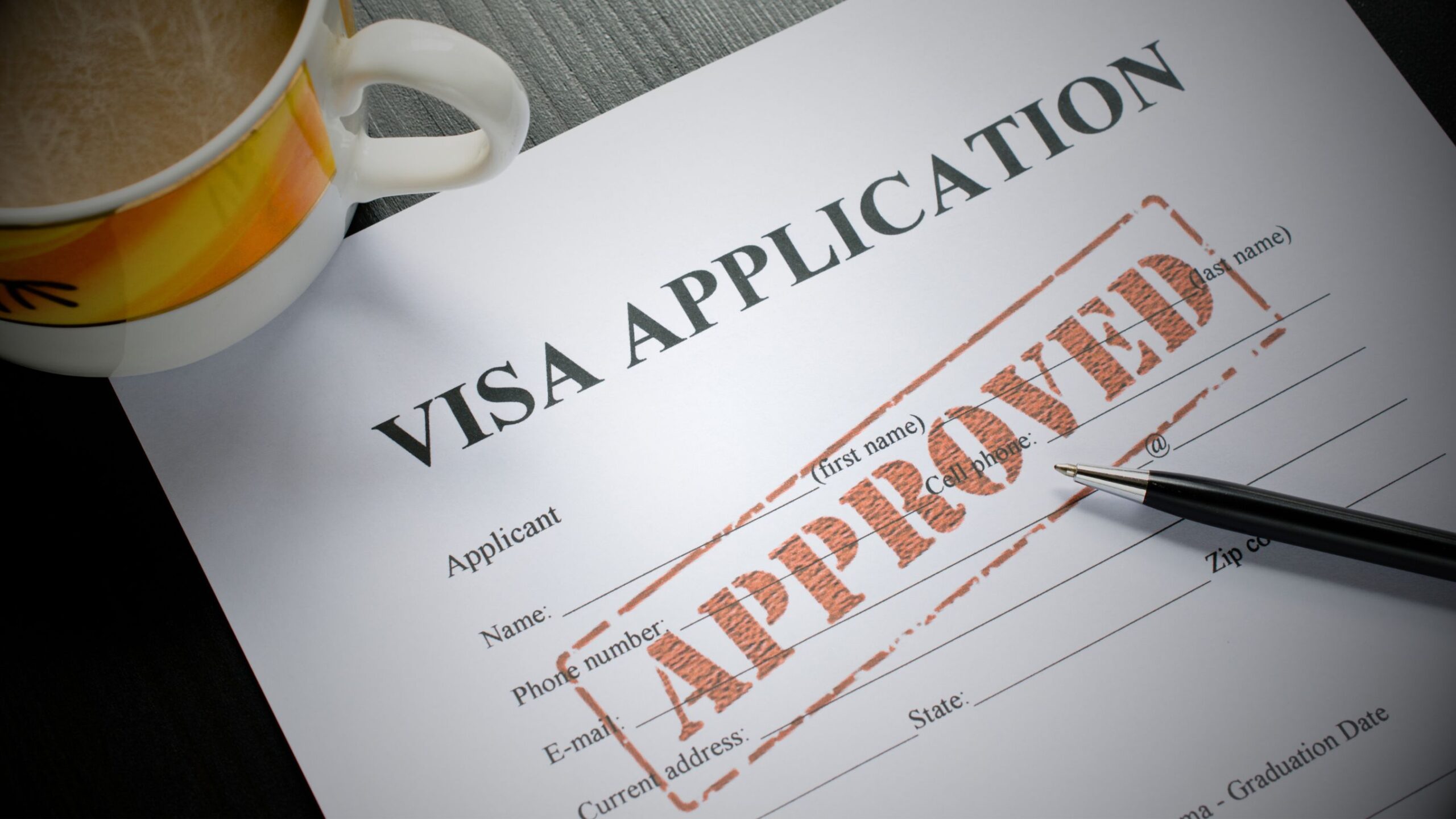 Approved Visa Application form with stamp and pen, used for Immigration.