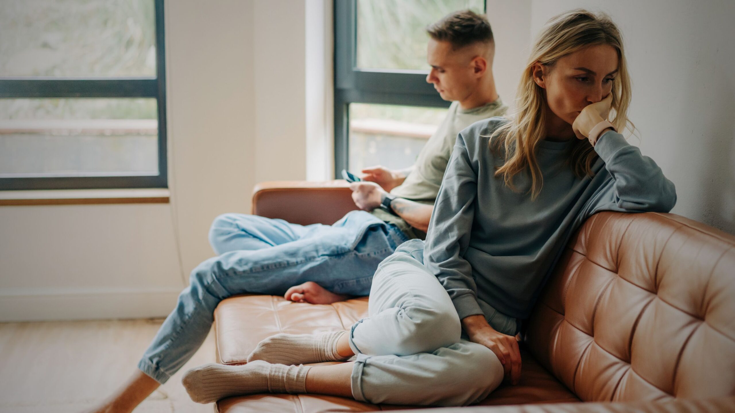 UK family law services, displaying VINTTRO partner divorce separation solicitors | couple sitting on sofa looking sad and distant about family matters.