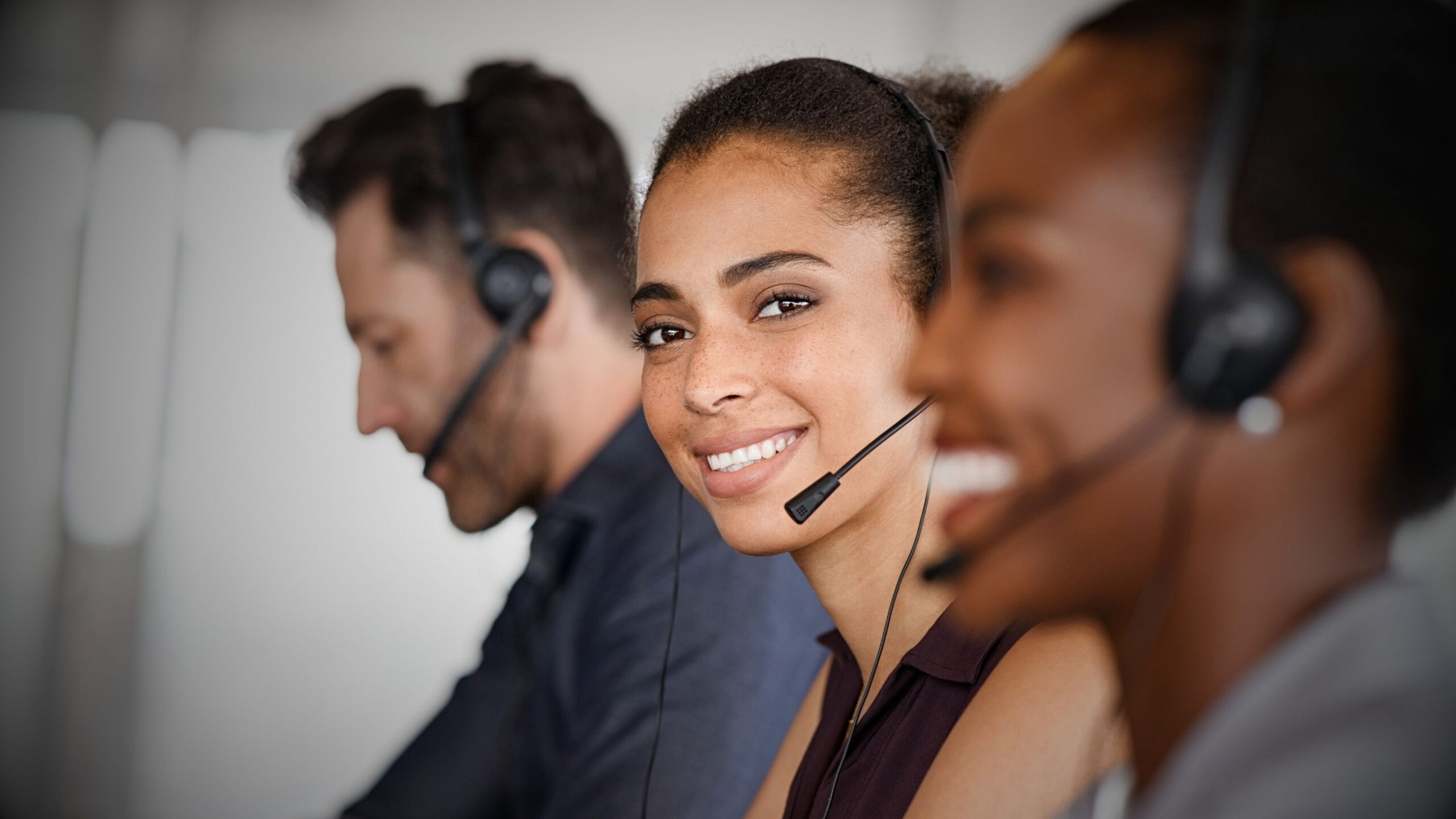Smiling VINTTRO Accident Management agent wearing a headset in a contact centre, providing dedicated customer service and first notification of loss (FNOL) support.
