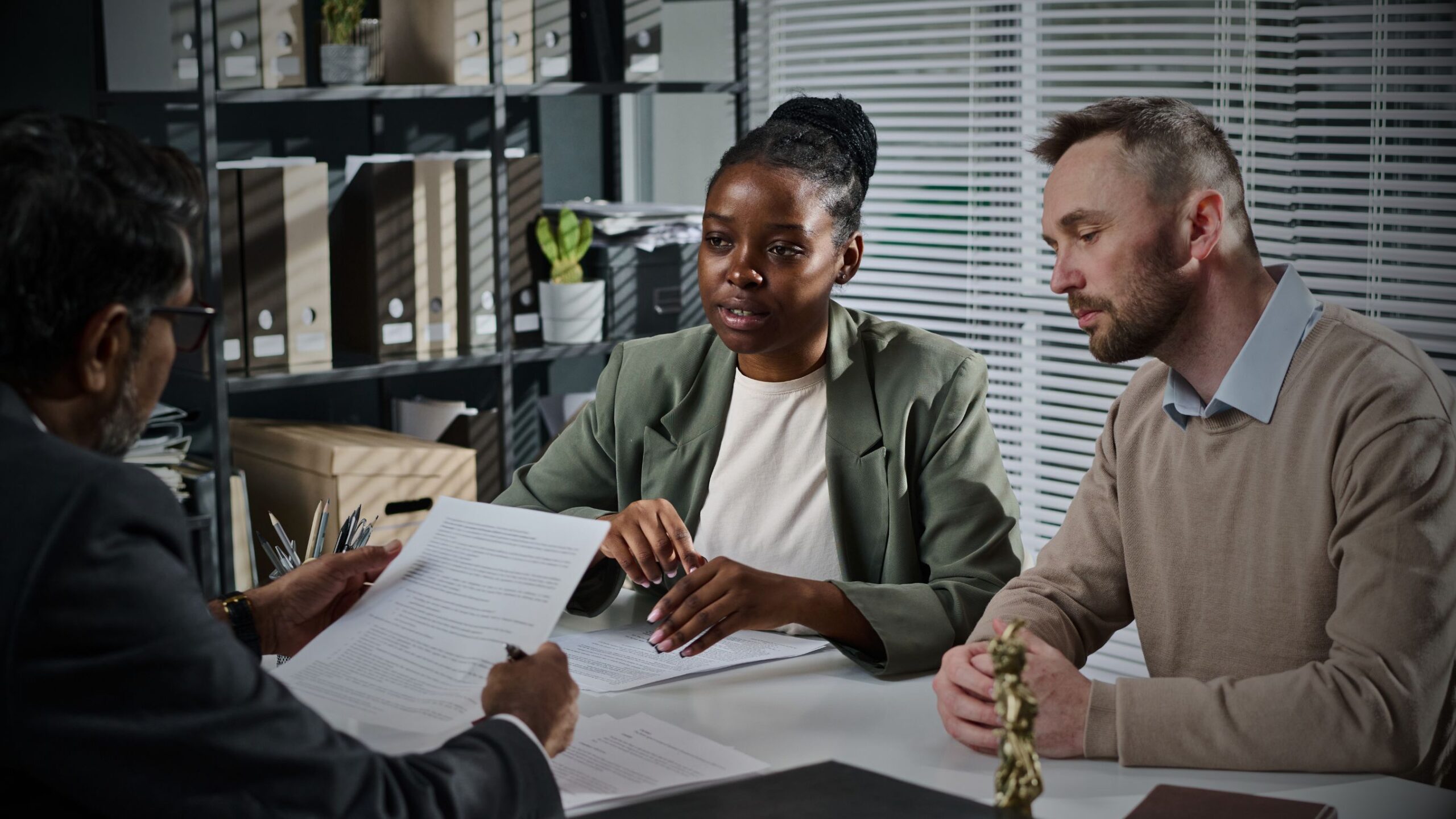Legal Consultation A couple sitting across a table reviewing claim documents with a legal professional in an office setting, symbolising expert consultation and support for motor claims litigation.