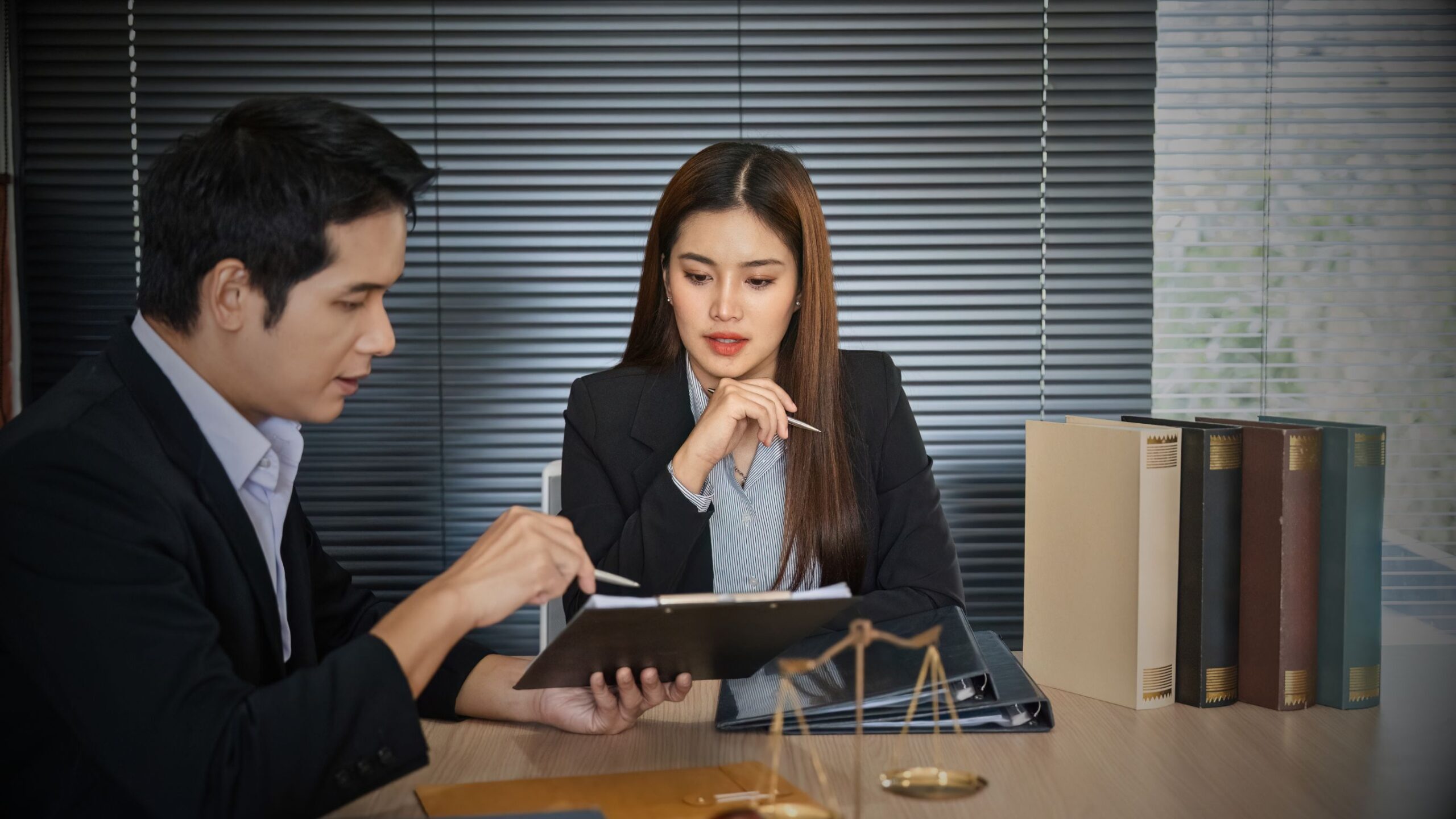 Two legal professionals reviewing documents with a scale of justice on the table, symbolising expert legal advice, claims litigation strategy, defence and recovery services.