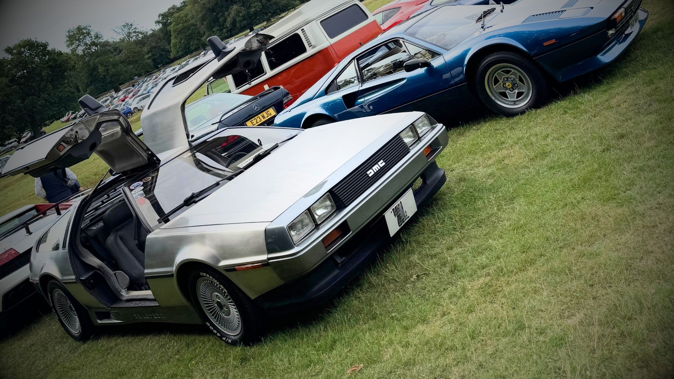 A pristine DeLorean DMC-12 with its iconic gullwing doors open, showcasing its brushed stainless-steel body and futuristic 1980s design.